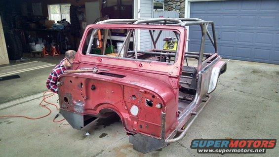 Red Jeep CJ body with roll cage, undergoing restoration