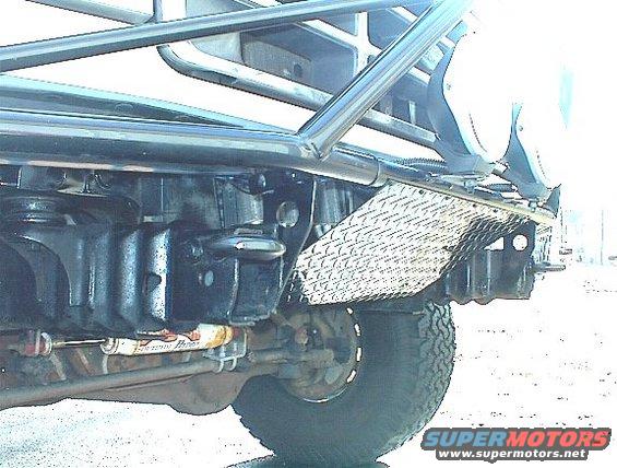 Close-up of off-road vehicle's front suspension and roll cage. Shows diamond plate and a shock absorber