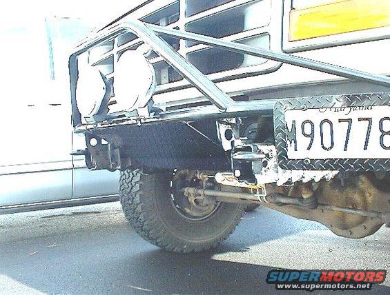 Rear bumper and tire of a white Ford Bronco with a custom brush guard and auxiliary lights