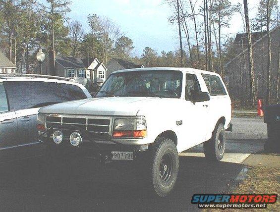 White 1995 Ford Bronco with aftermarket lights and a license plate reading 1907780