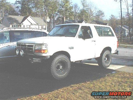 White 1995 Ford Bronco parked next to a silver minivan
