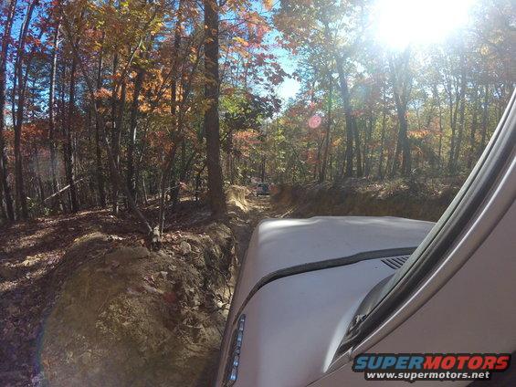 Driving on a dirt trail through autumn woods, sun shining