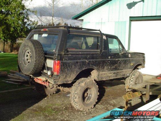 Black Ford Bronco with spare tire on back, parked outside a garage