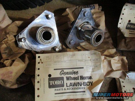 Two Toro Lawn-Boy wheel hubs with part tags. One hub is triangular, the other is rectangular