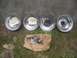 1986 Yamaha BLASTER - Four chrome wheels and two metal parts are laid out on the grass in front of a concrete wall.