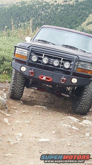 Front view of a 1996 Ford Bronco on a rocky trail, with a brush guard and winch