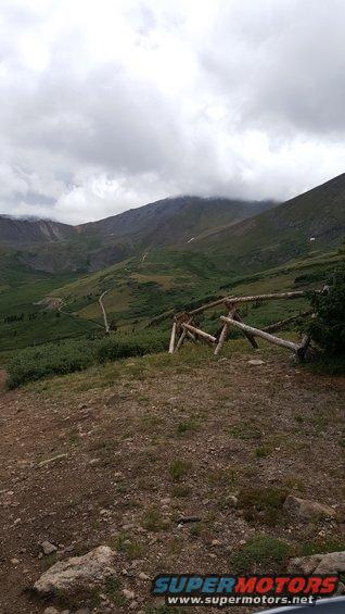 Mountain valley with a cloudy sky and a rustic wooden fence in the foreground