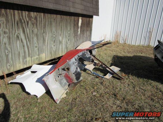 Wrecked red and white car parts on grass