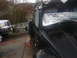 1964 Volkswagen Beetle - A black vintage car with a roof rack and auxiliary lights is parked outdoors next to a modern silver pickup truck.