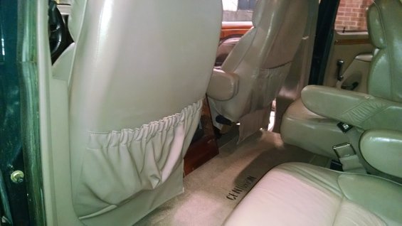 Interior view of a van showing tan leather captain's chairs and carpet with 'CENTURION' text