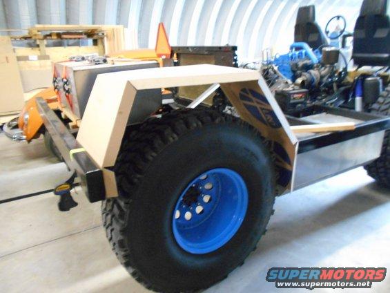 Custom off-road vehicle chassis with large tire, blue wheel, and unfinished body panels