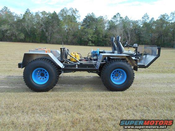 Custom off-road vehicle with exposed engine, blue wheels, and two seats, viewed from the side