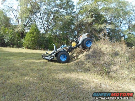 off-road utility vehicle with blue wheels on grassy hill