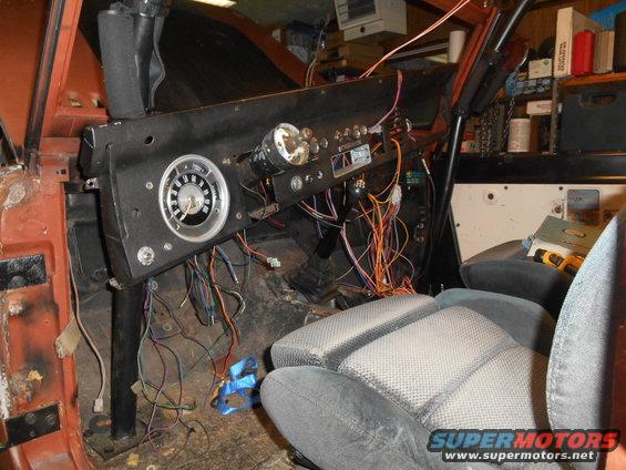 Interior shot of a vehicle's dashboard with exposed wiring and a gauge cluster