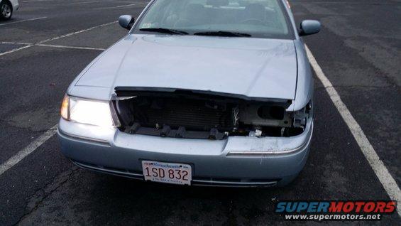 Front view of a light blue 2005 Mercury Grand Marquis with a damaged grille and missing headlights