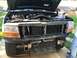 1995 Ford Bronco - The front of a dark green SUV is shown with the hood open, revealing the engine compartment and radiator.