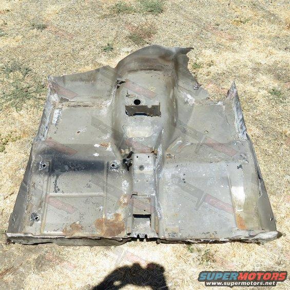 Corroded car floor pan with various holes and mounting points