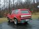 1990 Ford Bronco - This red Ford Bronco, likely from the early 1990s, is parked outdoors on a wet asphalt surface.
