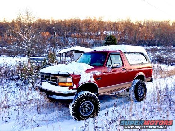 1995 Ford Bronco in snow, front quarter view. Snow covers the hood and roof