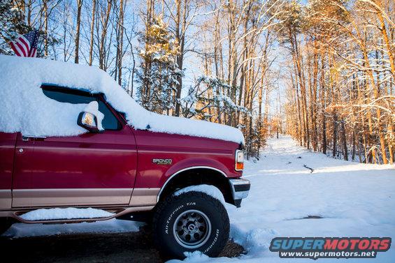 Red 1995 Ford Bronco in snow, side view with American flag