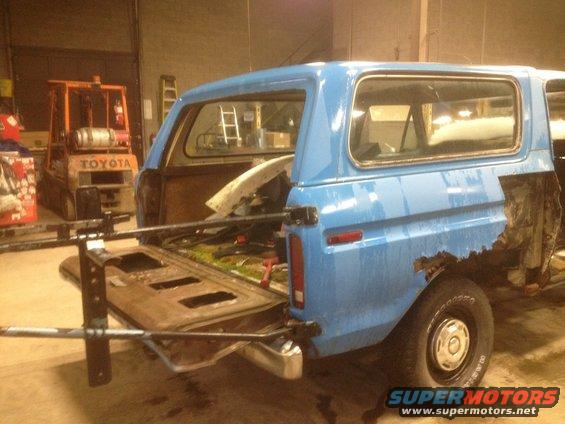 Blue 1979 Ford Bronco rear view with open tailgate and rusted quarter panel