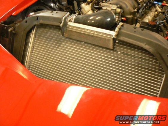 Red car's engine bay with exposed radiator and intake hose