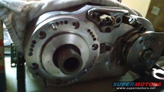 Close-up of a metal transfer case with bolts and a label that says "Front"