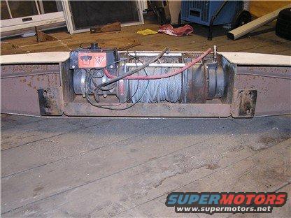 Winch mounted on a rusty bumper, with red and black cables