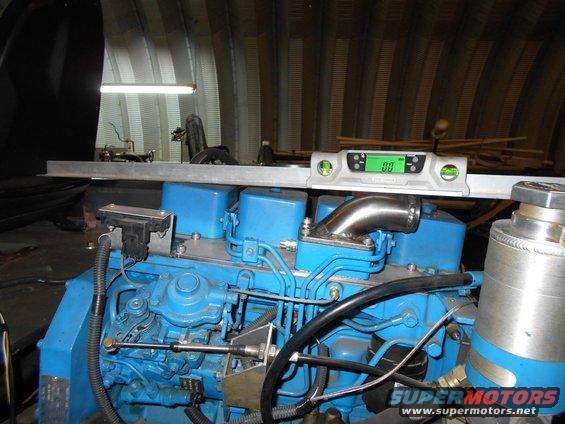 Close-up of a blue engine with a digital level on top. Some pipes and wires are visible