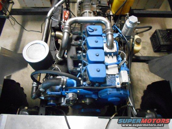 Blue engine with silver exhaust pipes and black air filter, viewed from above