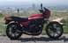 2008 Ford Crown Victoria - Red Kawasaki GP1100 motorcycle parked on gravel with a city skyline in the background.