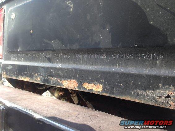 Rear panel text "FINS N THINGS STRIKE RAVINE" on black vehicle with rust