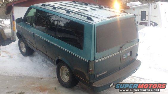 teal van parked in snow, rear view. License plate visible