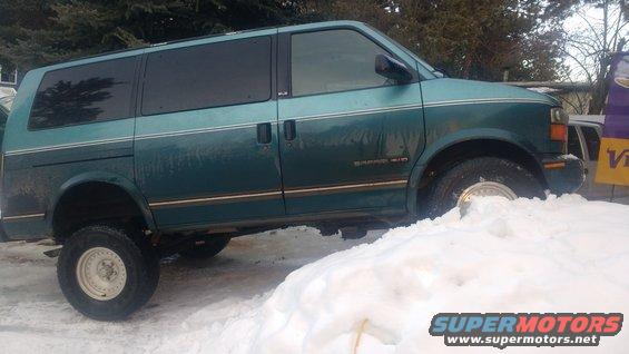 Green 1995 GMC Safari van with lifted suspension stuck in snow, side view