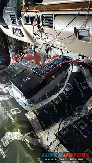 Interior of a vehicle with sound deadening material on the floor and wires running everywhere