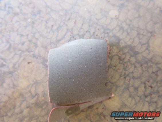 close-up of gray foam piece on patterned surface, with 'SUPERMOTORS' watermark