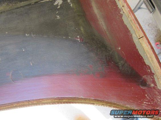 close-up of the inside of a car fender, showing red paint and some scuff marks