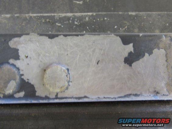 Close-up of peeling paint on a metal part with two rivets visible