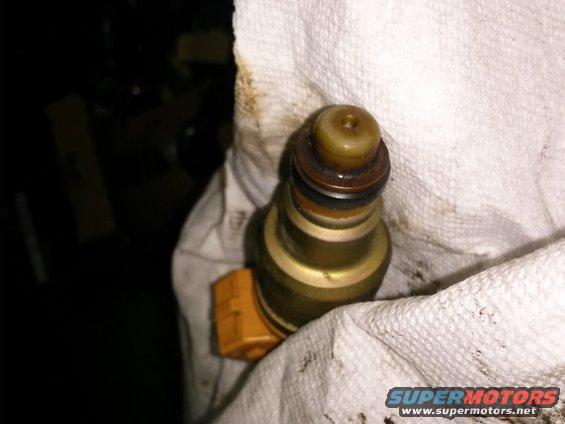 Close-up of a fuel injector, possibly dirty, resting on a white cloth