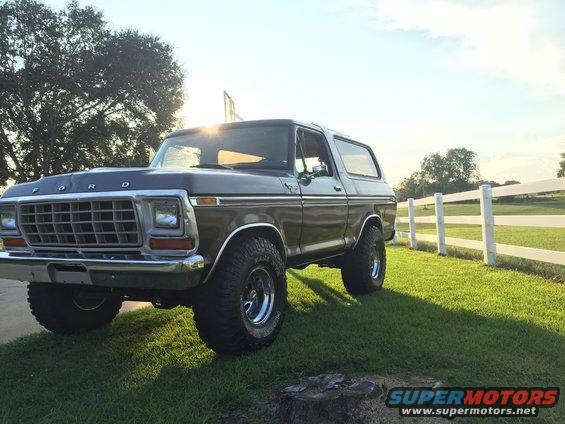 Dark brown 1978 Ford Bronco parked on grass near a white fence