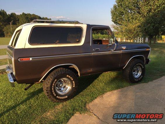 Brown and white 1978 Ford Bronco with chrome wheels and roof rack, parked on grass