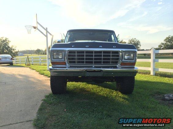 Dark blue Ford truck front view, grille with F-O-R-D lettering, chrome bumper, on grass next to driveway
