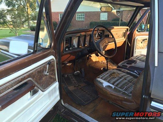 Interior view of a brown pickup truck, showing the dashboard, steering wheel, and worn seats