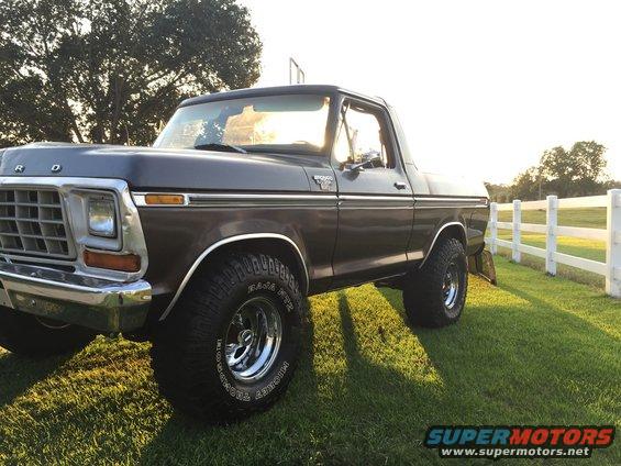 1978 Ford Bronco parked on grass near a white fence
