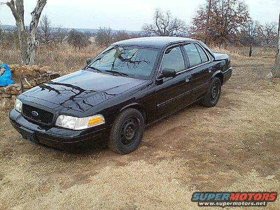Black 2009 Ford Crown Victoria parked on dirt, 3/4 front view