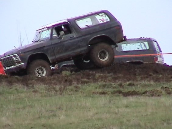 Dark SUV with off-road tires climbing a muddy hill, 1978 model year suggested by grille