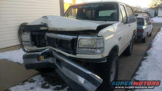 White SUV with front-end damage, parked next to a sedan. Snow on the ground