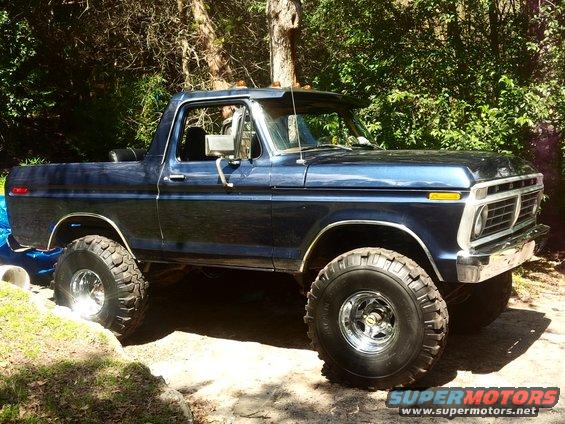 Blue pickup truck with large tires and chrome wheels, 3/4 front view