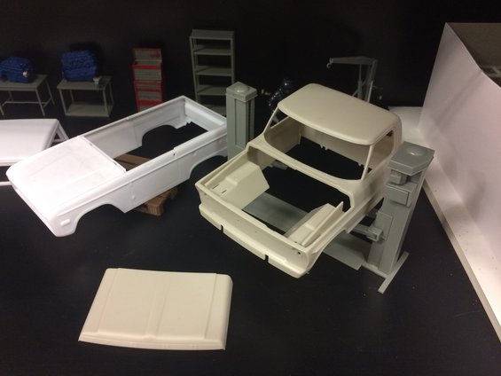 Unassembled model kit parts for a truck and a Ford Bronco body, with engine models in the background
