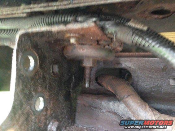 Close-up of rusty vehicle undercarriage with brackets and wiring.
